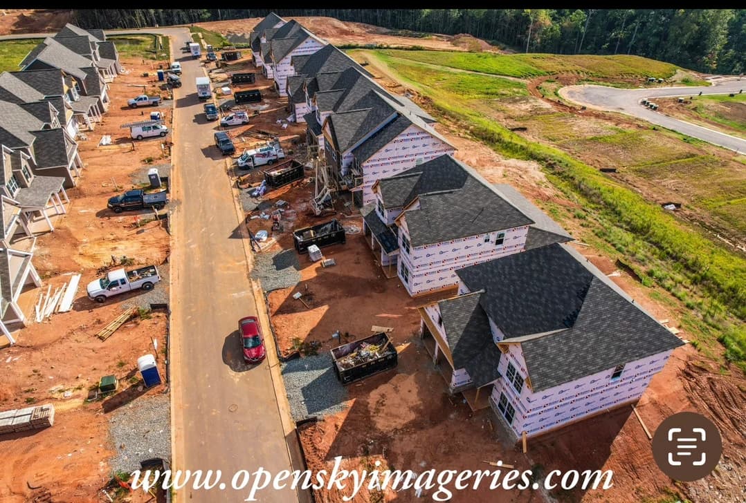 Aerial view of homes under construction beside graded land.