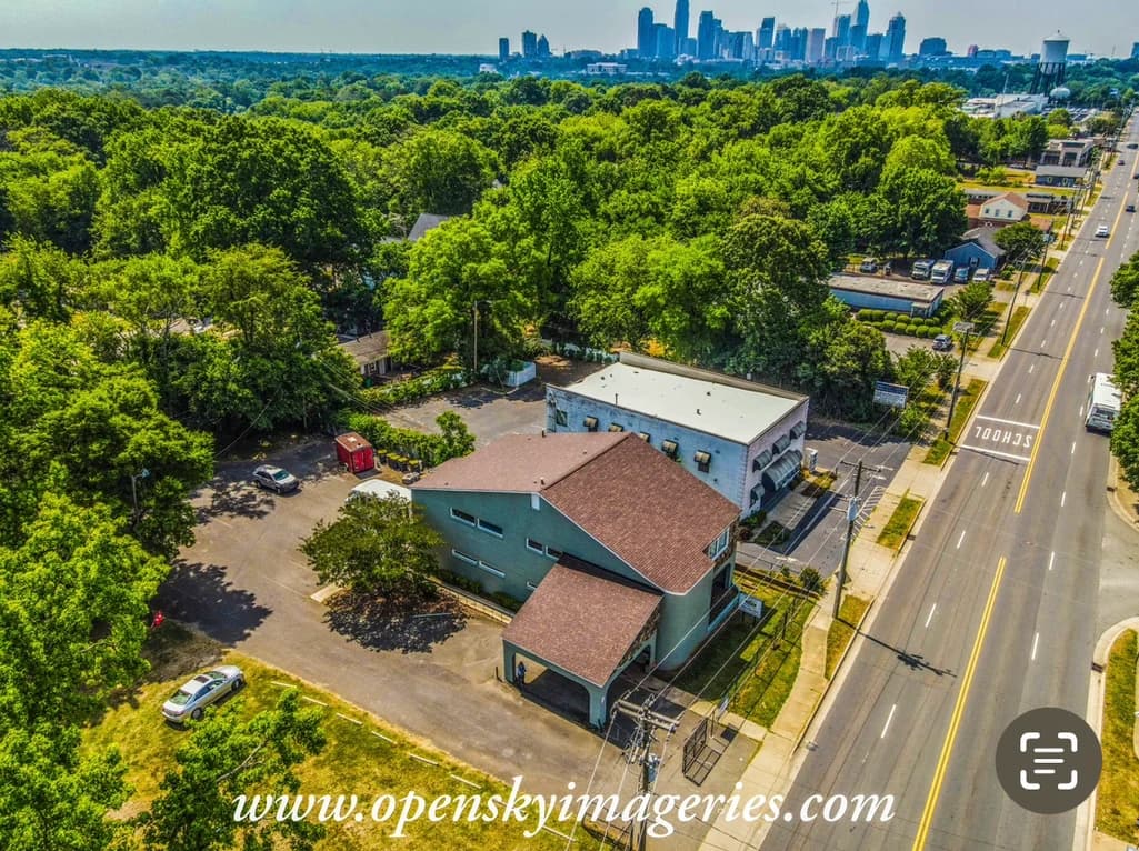 Aerial view of tree-covered neighborhoods and a distant city skyline.
