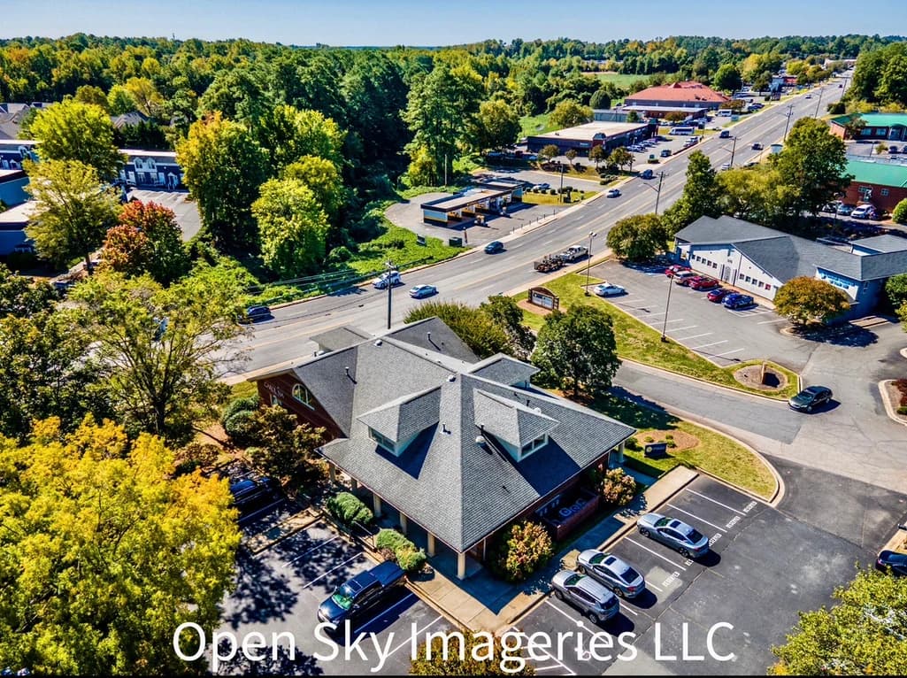Aerial view of a low-rise property surrounded by roads, parking, and tree cover.