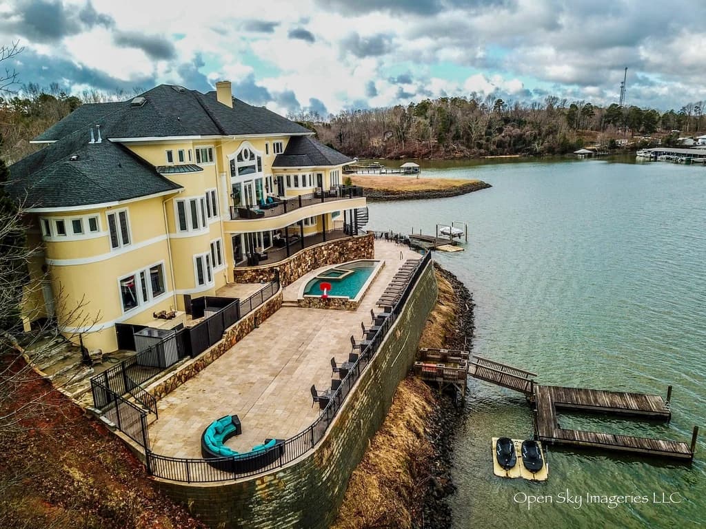 Aerial view of a waterfront home, grounds, and adjoining dock.