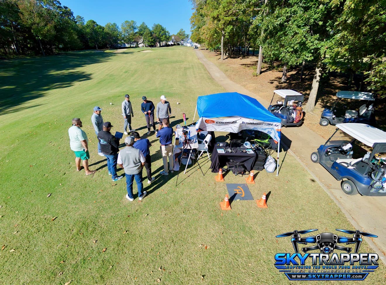 Aerial drone photograph of attendees networking at the Open Sky Imageries LLC and Building With Blu booth beside a golf fairway during the JCS Builder Appreciation Golf Tournament in Charlotte, North Carolina.